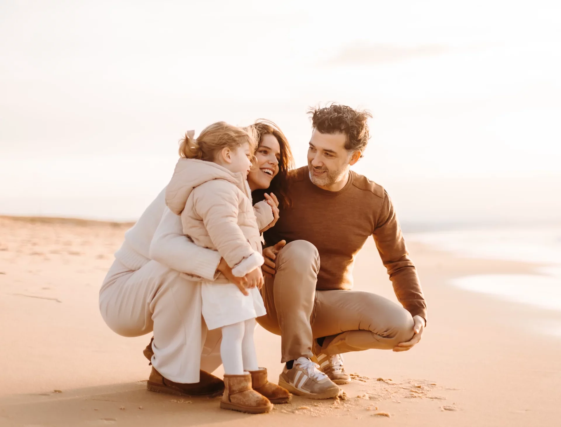 Famille heureuse sur la plage de Capbreton : femme enceinte, mari et petite fille au coucher du soleil, teintes beige et ambiance chaleureuse dans les Landes